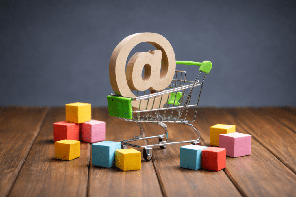 Mini shopping cart with @ symbol and colorful blocks representing ecommerce and online marketing